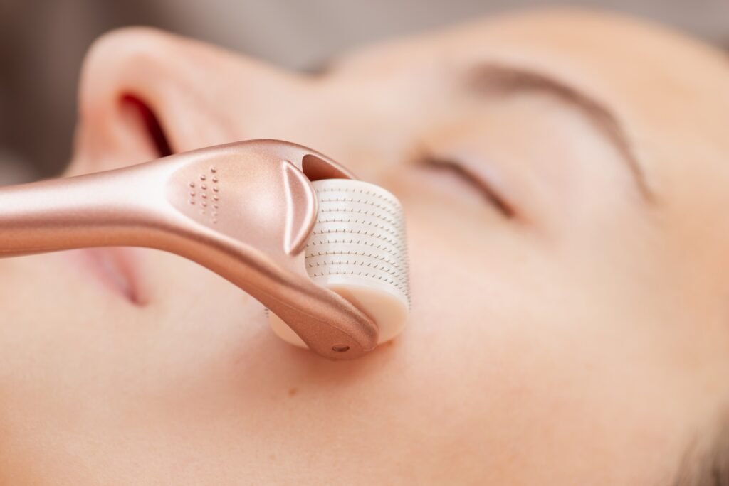 Using roller with micro needles for stimulation of skin regeneration and introduction of various rejuvenating drugs. Microneedle mesotherapy in cosmetology salon, close up of face of a girl client